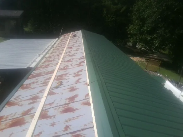 Old rusted panels beside newly installed green metal roofing — Wind Damage Roof Repair by Roofing Brothers in Golden Valley
