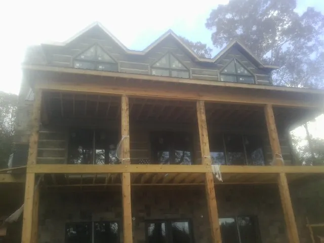 Dormers and porch framing on a large log home under construction — Roof Coating work by our crew in Golden Valley