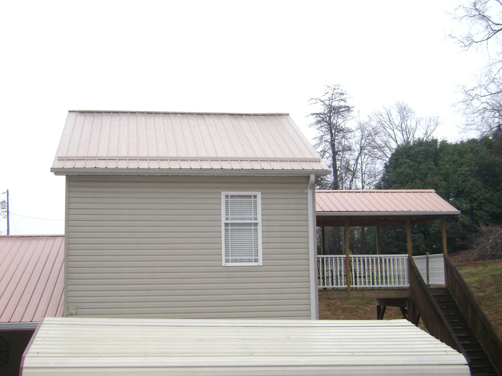 Tan metal roofs on a two story addition and attached porch, from a Roof Replacement job in Golden Valley