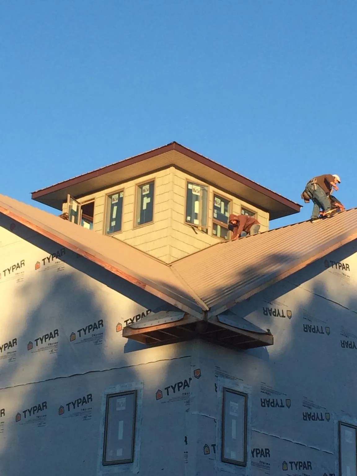 Roofers working around a rooftop cupola on a new metal roof at sunset — Roof Waterproofing in Golden Valley by Roofing Brothers